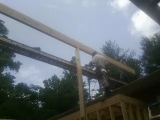 Carpenter setting a ridge beam over a new addition frame — Ice Dam Removal by Roofing Brothers in Greenfield Center