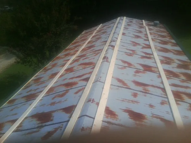 Rusted metal roof panels with new wood purlins before replacement — Storm Damage Roof Repair in Greenfield Center by Roofing Brothers