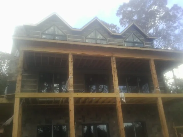 Dormers and porch framing on a large log home under construction — Roof Coating work by our crew in Greenfield Center
