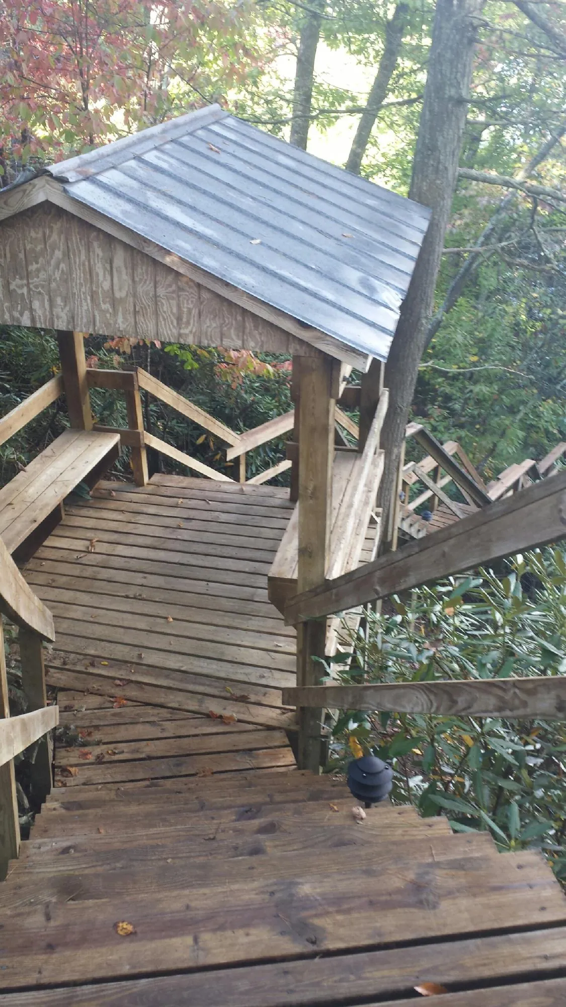 Metal roofed shelter over wooden steps on a wooded walkway — Skylight Repair & Installation work by our crew in Greenfield Center