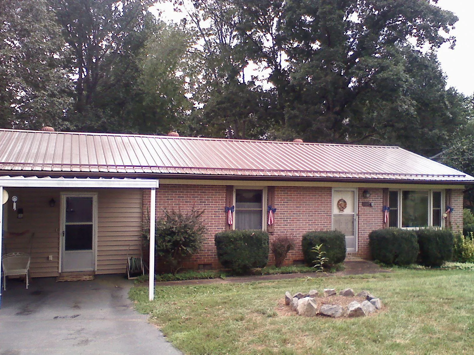Bronze metal roof and carport on a brick ranch home — Roof Repair work by our crew in Greenfield Center